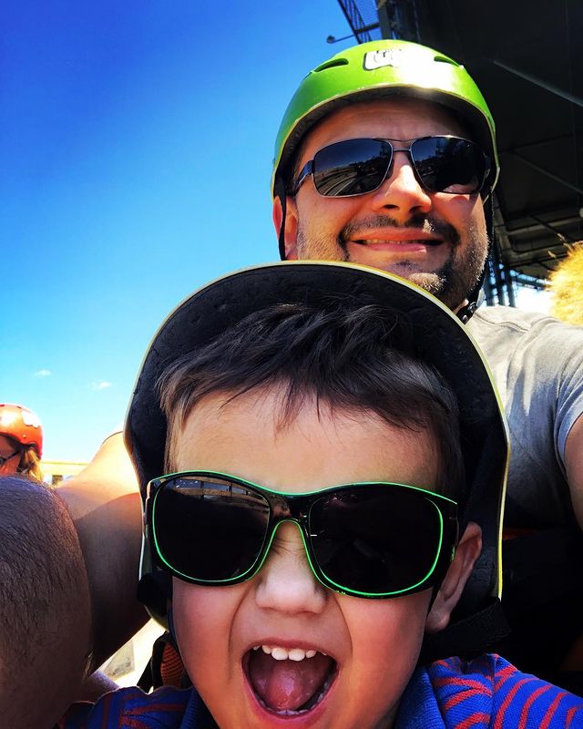 Lennox Hastie in a green helmet with his son in a green helmet and black goggles with green borders.